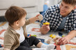 © New Africa - Smiling male nanny and cute little boy playing with toys on floor at home, selective focus