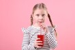 © New Africa - Little girl drinking fresh pomegranate juice on pink background