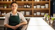 © Rizal - Smiling Waitress in Green Apron Standing by Restaurant Bar with Shelves of Drinks and Dishes