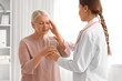 © Pixel-Shot - Mature woman taking glass of water from gynecologist in clinic. Menopause concept
