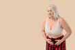 © Pixel-Shot - Mature woman with menstrual cramps on beige background. Menopause concept