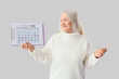 © Pixel-Shot - Mature woman with menstrual calendar on light background. Menopause concept