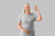 © Pixel-Shot - Mature woman showing OK on light background. Menopause concept