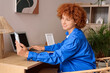 © Pixel-Shot - Young redhead woman using laptop with mobile phone at home