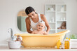 © Pixel-Shot - Young mother bathing her baby at home
