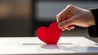 © SHIMA - Hand casting a heart shaped vote into a ballot box