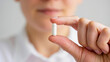 © NikProArt - Close up of a persons hand holding a single white capsule pill.