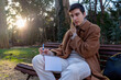 © Martí Rosselló - Young man making phone call writing notes in park