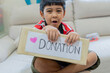 © Kunlathida - Cute little Asian boy holding donation cardboard box with at home.