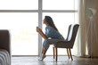 © Prostock-studio - Side view of pretty young woman drinking hot coffee in cozy chair near window indoors, copy space. Peaceful millennial lady having relaxing day, chilling on lazy morning indoors