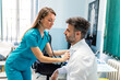 © Graphicroyalty - Female doctor in blue scrubs using stethoscope to listen to male patient's heart. Professional healthcare specialist performing chest auscultation during a clinical medical consultation.