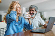 © Lumos sp - Portrait of a lovely senior mature couple using a laptop together and having fun drinking coffee or tea sitting at a table at home