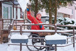© Alex - A man in a red jacket in a wheelchair shoveling snow from a ramp with a snow shovel