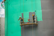 © chitsanupong - The male worker takes the cable car holding an industrial painting brush used for shell plate tank oil surface surface green