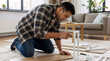 © OlgaNeuroArt - Focused man assembling new flat-pack furniture in his living room. Handyman building a shelf with a screwdriver. DIY home improvement project