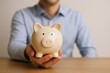 © The Little Hut - Man Holds Piggy Bank in Hand, Saving Money Concept, Financial Planning and Investment for Future