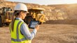 © crispy - Female industrial worker using a digital tablet in a quarry. Modern mining operations and construction site management concept for a digital future