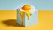 © BlackLion - Fresh egg on blue block with yellow background and yolk dripping down