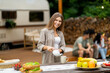 © Prostock-studio - Pretty Caucasian woman pouring tea, making breakfast near motorhome, camping with her multinational friends outdoors. Cool young lady enjoying her summer vacation, resting in countryside
