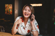 © BullRun - Close-up of cheerful Asian woman holding phone and stylus, expressing happiness, connection, and creative communication in modern freelance lifestyle.