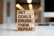 © FATNA - Wooden blocks with words 'Set goals crush them repeat'.