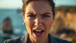 © Segati - A close-up portrait of an angry woman with a blurred background of ocean and cliff