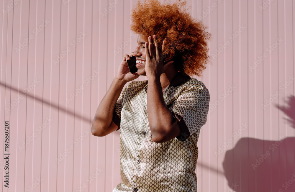 Smiling African American man with curly red afro holding smartphone ...