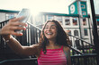 © BullRun - Young woman proudly smiling during selfie, tongue out, full of character and charisma. Celebrating digital presence, unfiltered expression, and self-love through mobile interaction.