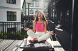 © BullRun - Young woman sits cross-legged, eyes closed mid-laugh, practicing joyful meditation. Scene of digital balance, personal energy, and authentic feminine presence.