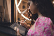 © BullRun - Side view of Hispanic woman with curly hair using stylus on tablet, wearing floral pink dress, demonstrating mobile productivity, freelance independence, and digital creative work.