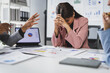 © Wasan - Business team engaging in a tense discussion about disappointing financial results during a corporate meeting, with a stressed businesswoman hiding her face in her hands, overwhelmed by the news.