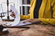 © Wasan - Legal advice concept. Female lawyer reviewing contract documents on wooden table in office.