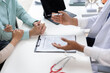 © Wasan - Doctor explaining medical service agreement to couple, health insurance policy terms, medicine service contract details, or signing healthcare plan document.