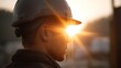 © Bussakon - Worker in hard hat at sunrise illuminated by sun s rays and flare
