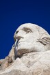 © Mint Images - Close view of George Washington carved in granite at Mount Rushmore National Memorial under a clear blue sky in the Black Hills of South Dakota.