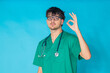 © carballo - young doctor isolated in background with an okay expression