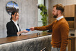 © Serhii - Hotel guest checking in at reception desk