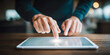 © Bonsales - Person using fingertip to interact with a digital tablet on a wooden desk, symbolizing innovation and internet access
