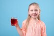 © New Africa - Little girl with glass of pomegranate juice on light blue background