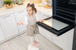 © New Africa - Child safety at home. Little girl opening oven in kitchen