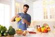 © New Africa - Man pouring juice into glass at table in kitchen