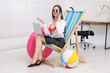 © New Africa - Woman with laptop talking on phone on deckchair in office