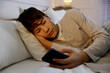 © New Africa - Teenage boy with smartphone in bed at home