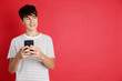 © New Africa - Teenage boy using smartphone on red background, space for text