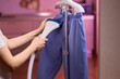 © Евгений Вершинин - Blue shirt steaming, Blue uniform hanging while expertly steamed for wrinkle removal, Navy blue outfit on hanger being carefully steamed to remove creases professionally
