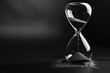 © Sandu - Hourglass filled with black sand sits on a dark surface during evening light