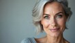 © miss irine - Mature woman with short grey hair and bright blue eyes smiles gently. Her facial skin looks healthy and radiant. She has a calm and confident expression, exuding natural elegance and grace.
