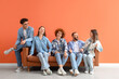 © Pixel-Shot - Group of young friends sitting on sofa near orange wall