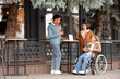 © Pixel-Shot - Young woman in wheelchair and her friends with coffee at street cafe