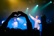 © Monostereo 88 - Silhouette hands making heart shape at live concert with blue stage lights